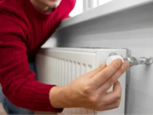 una mano sulla valvola per regolare un termosifone