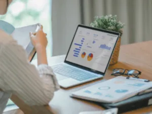 una persona di spalle a una scrivania con un pc portatile e un agenda
