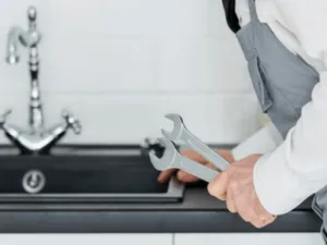 idraulico all'opera ripara la tubazione di un lavandino