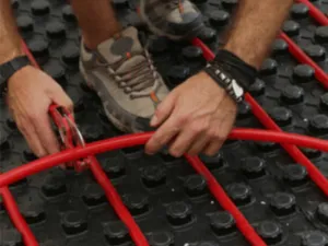 un operaio fa manutenzione ad un impianto termoidraulico a pavimento